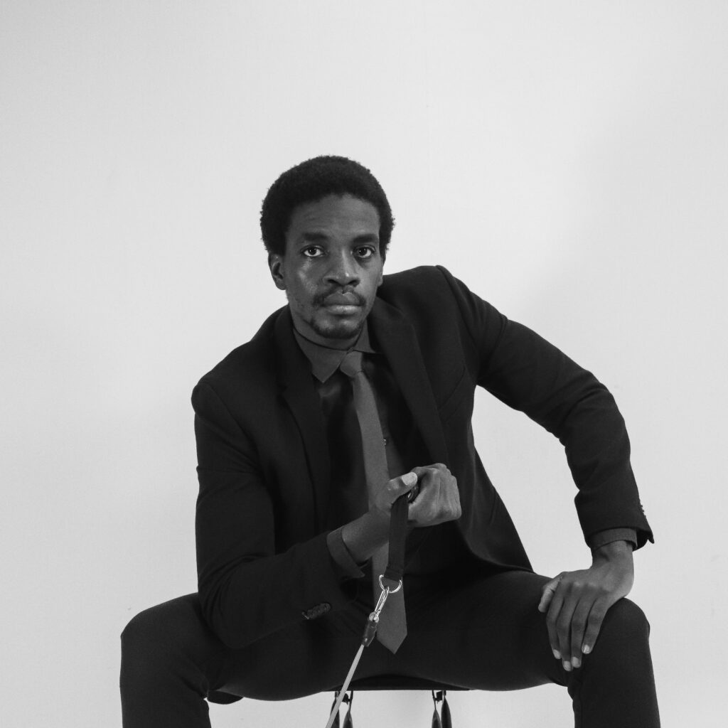 Monochrome portrait of an African American man sitting thoughtfully in a studio.
