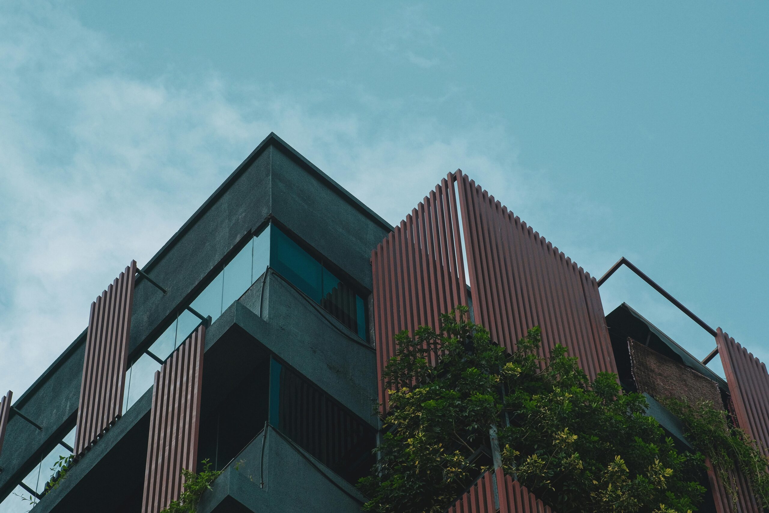 Angle view of a modern tropical building with vertical slats and greenery.