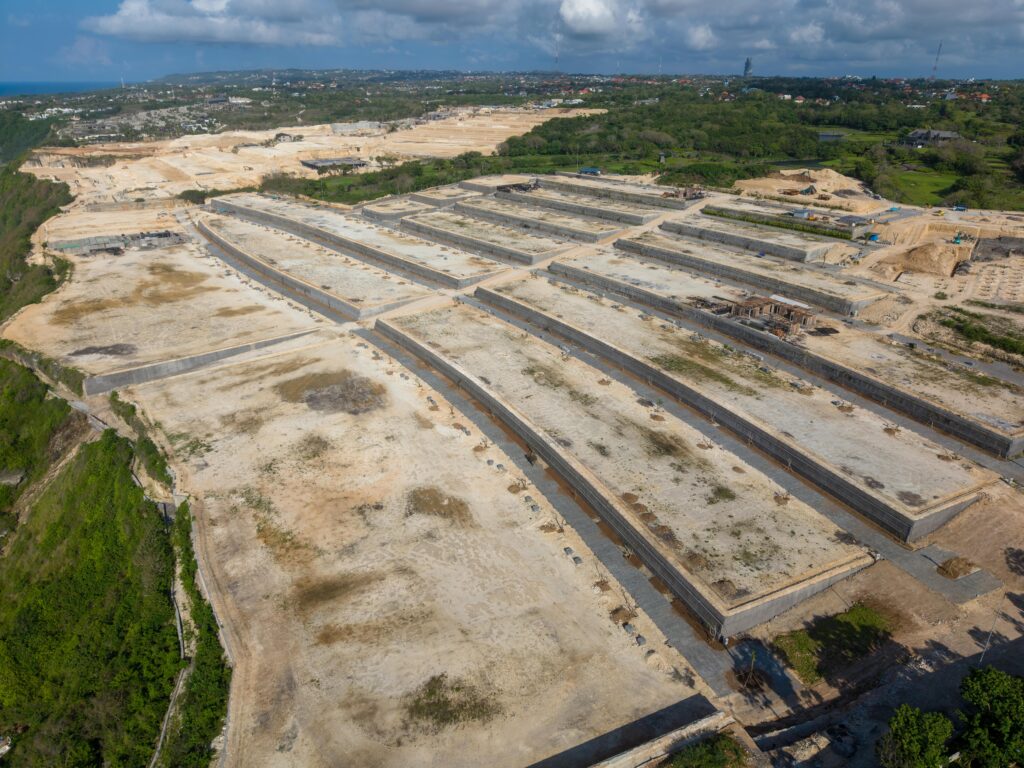 Expansive aerial view of a large construction site in Bali, Indonesia under a cloudy sky.